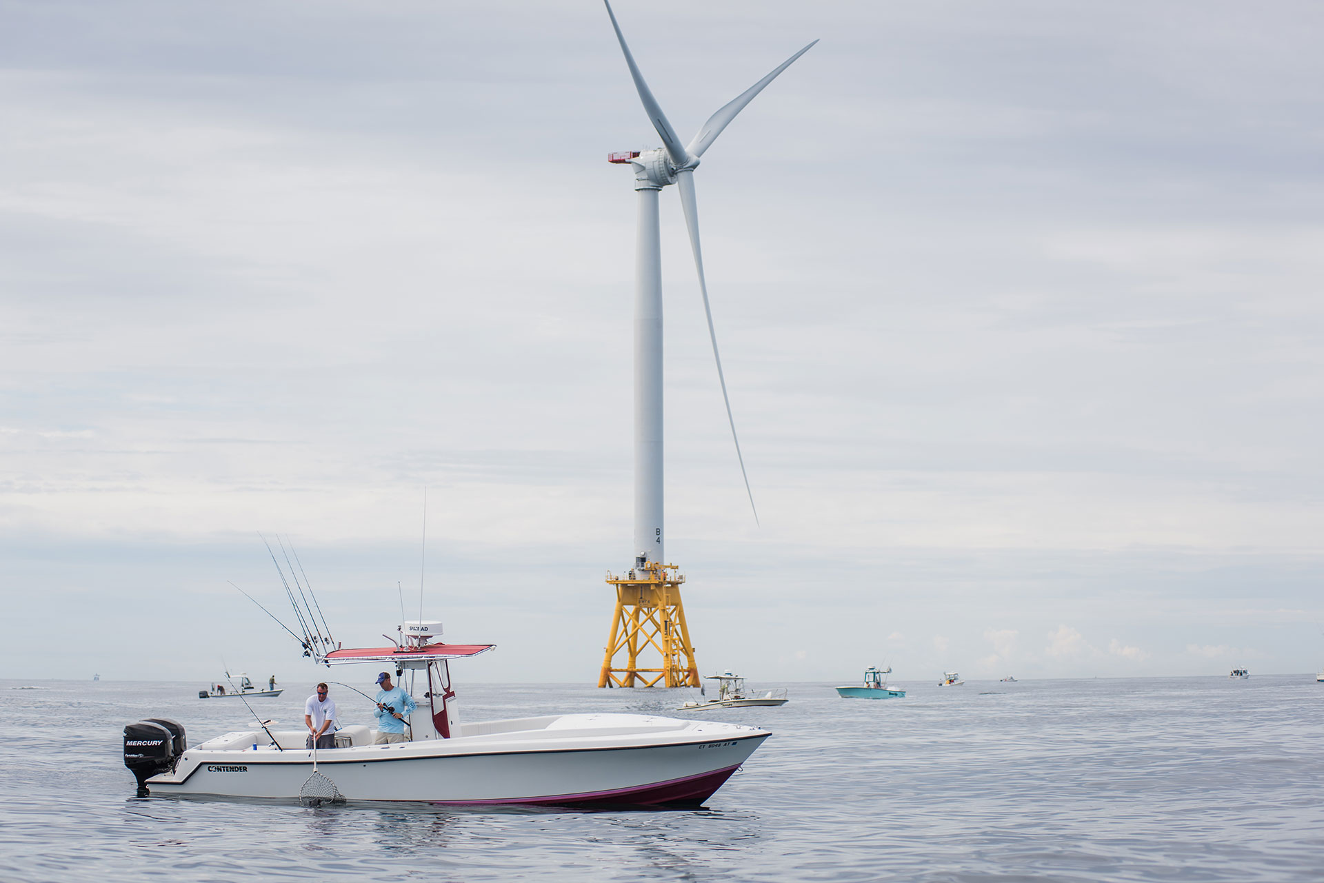 Two Men Fishing on a Boat with a Wind Turbine in the Background